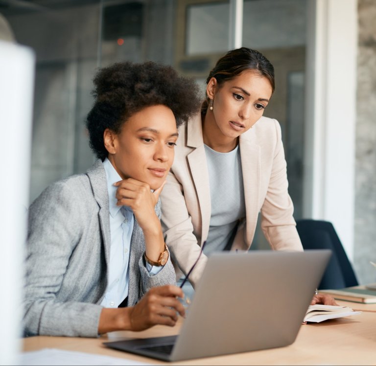 businesswomen-cooperating-while-working-on-laptop-with-Microsoft